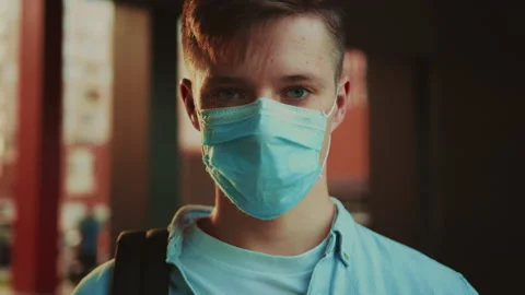 Student in a mask watching at the camera. Close-up portrait of young man with Stock Footage 141558243