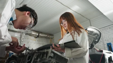 Student Measuring Engine Dimensions While Colleague Records Data in Automotive Stock Footage 303063927