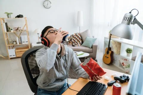 Student in messy dormitory drinking can of beer Stock Photos