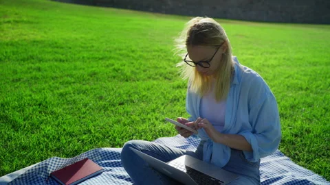 Student multitasking on laptop and smartphone while sitting on checkered bl.. Stock Footage 318239540