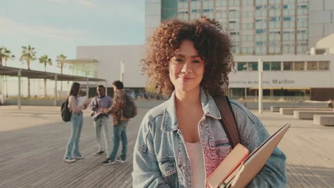 Student with notebooks in her hands looks at the camera and smiles Stock Footage 227383282