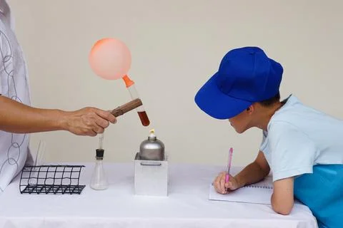 Student is observing, taking note about the reaction of balloon on test tube Foto stock