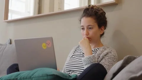 Student or freelancer working from home on laptop computer sitting on couch Stock Footage 293494166