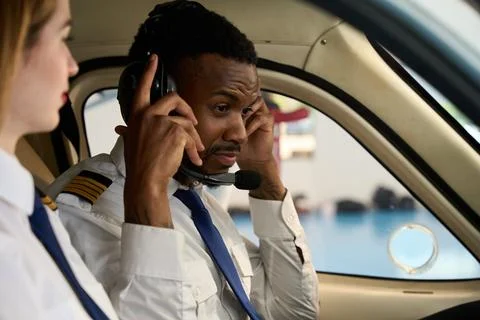 Student pilot adjusting headset in cockpit with instructor beside him Foto stock