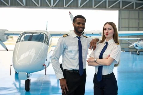 Student pilots posing in front of aircraft in hangar Stock Photos