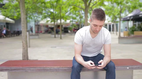 Student playing with electronic device, sitting on the bench Stock Footage 39343165