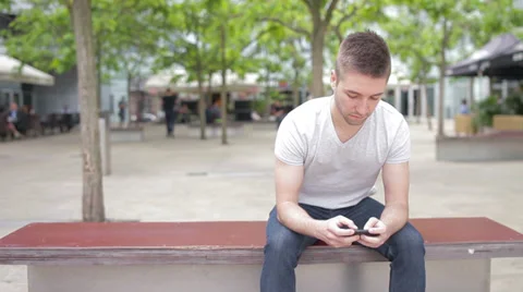 Student playing with electronic device, waiting on the bench Stock Footage 39343168