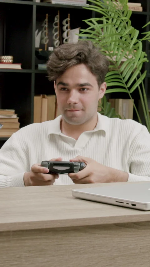 Student plays game with controller at desk in study area Stock Footage 313927693