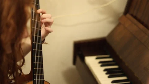 Student practicing classical guitar during a music lesson with piano Stock Footage 340183844