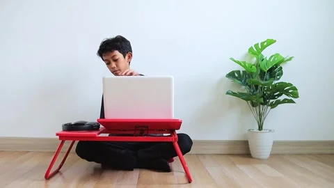 Student prepares for remote learning, putting on headphones to begin his class Stock Footage 324948150