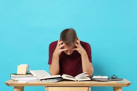 Student preparing for exam at table against light blue background Stock Photos