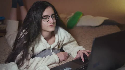 Student preparing homework on laptop lying in bed in the evening, home teaching Stock Footage 152655561