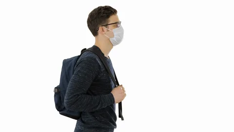 Student in protective masks walking with backpack on white background. Stock Footage 129463995