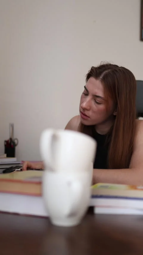 Student pushes through fatigue with coffee during exam preparation Stock Footage 340087586