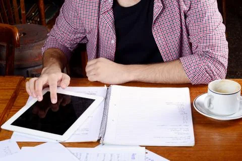 Student reading and using tablet with a cup of coffee. Stock Photos