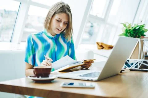 Student reading book and using laptop in cafe Stock Photos