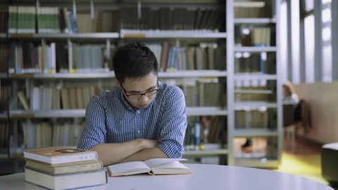 Student reading book at desk in library in college. Flipping book pages Stock Footage