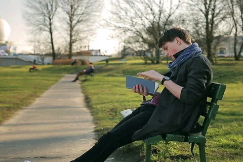 Student reading book in the park and sitting on the bench Video stock 48270699