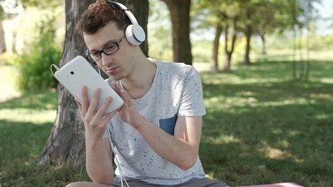 Student reading book in the park and smiling to the camera, steadycam shot Vídeos de archivo 78625653