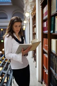 Student reading at bookshelf Foto stock