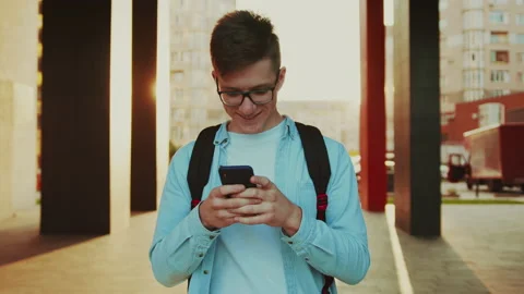 Student reading something funny at the smartphone. Video portrait of handsome Stock Footage 141557557