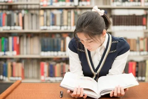 Student reading a textbook in library Stock Photos