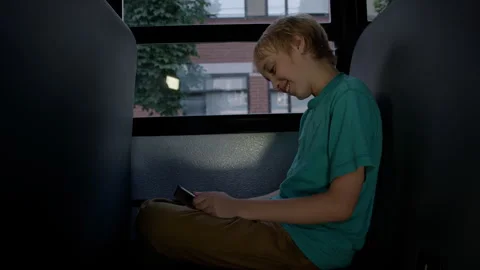 A Student on school bus on his device driving home from class Stock Footage 337164379
