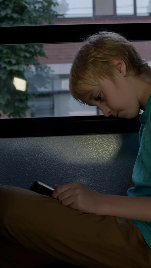 A Student on school bus on his device driving home from class gets cyber bullied Stock Footage 337164410