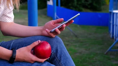 A student, a schoolboy with an apple in his hands and a smartphone outdoors Stock Footage 208419416