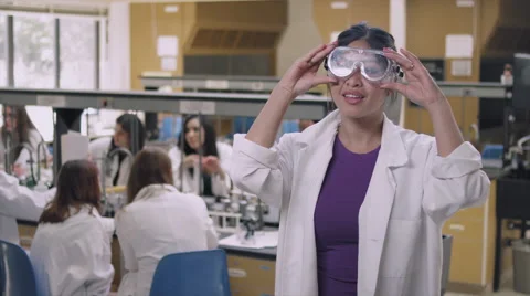 Student in a science lab putting on safety goggles and smiling 库存影片 58859429