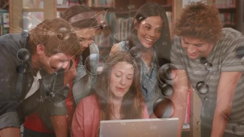 Student scrolling laptop in library activating network graphics while peers Stock Footage 320089820
