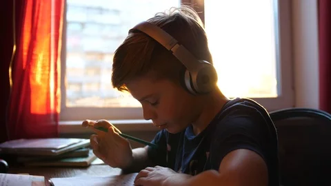 The student is sitting at a Desk and does its job. School education. The sun's 库存影片 87507184