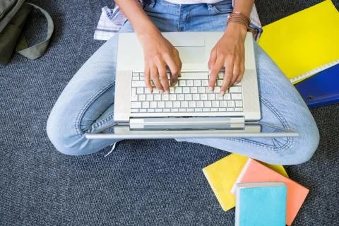 Student sitting on floor in library using laptop 스톡 사진