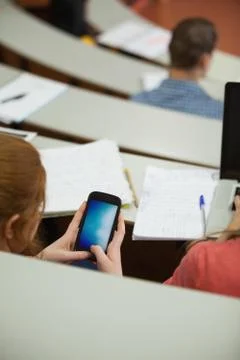 Student sitting in a lecture hall using her smartphone Fotos de archivo