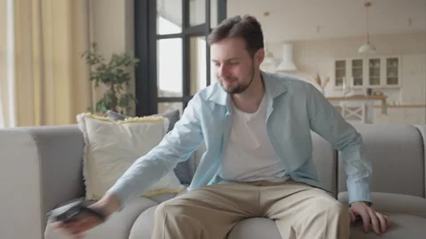Student Sitting On Sofa, Picking Up Controller And Starting Video Game Session Stock Footage 304582009