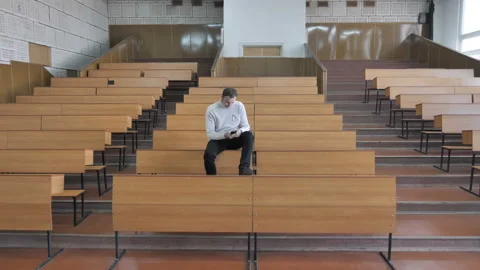 Student Sitting On The Table And Use The Smartphone In Empty Auditorium Stock Footage 127420511