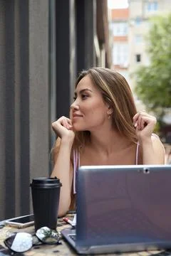 Student sitting at table outside of cafe, studying with laptop, doing homework Stock Photos