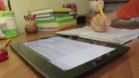 Student Sitting At Table Studying With Tablet Writing In Notebook. Vídeo Stock 49927452