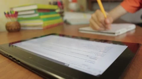 Student Sitting At Table Studying With Tablet Writing In Notebook. Vídeo Stock 49930950
