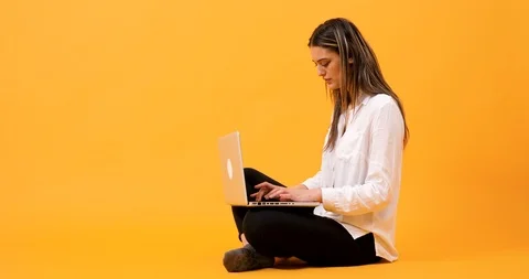 Student sitting on an yellow background Stock Footage 103031325