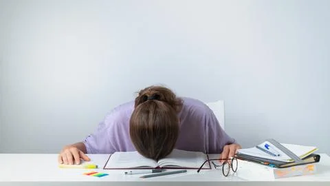 A student sleeps on a textbook - difficult study, heavy load Stock Photos
