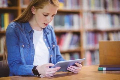 Student with smartwatch using tablet in library 写真素材