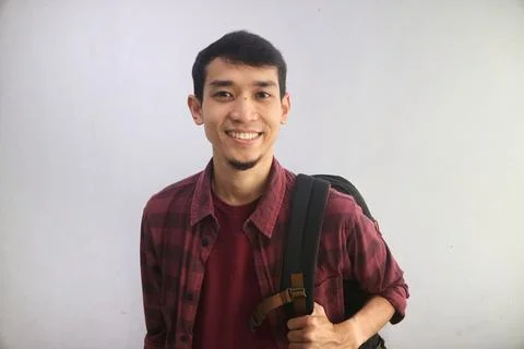 A student smiles confidently while carrying backpacks Stock Photos