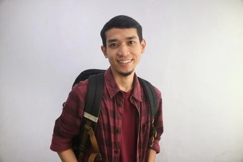 A student smiles confidently while carrying backpacks Stock Photos
