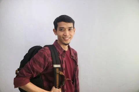 A student smiles confidently while carrying backpacks Stock Photos