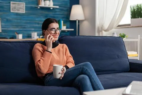 Student smiling while talking on phone holding cup of coffee Fotos de archivo