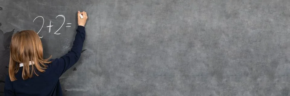 The student solves a math problem standing at the blackboard in her classroom 写真素材