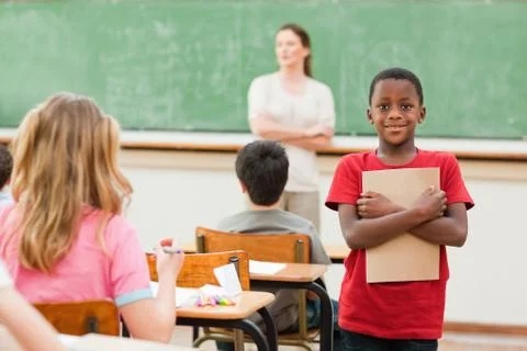 Student standing in class with his exercise book Stock Photos