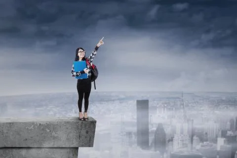 Student standing on rooftop and pointing at sky Ilustración de archivo