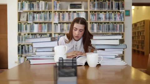 Student studies alone among books and coffee cups during exam preparation Vidéo 341655443
